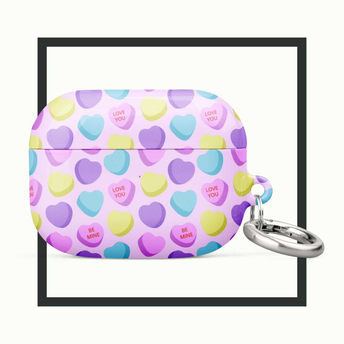 A pastel AirPods® case featuring a vibrant candy heart pattern with loving messages like "Love You" and "Be Mine." The case includes a metal carabiner for easy carrying and combines style with premium protection. Perfect for Valentine’s Day or everyday use!