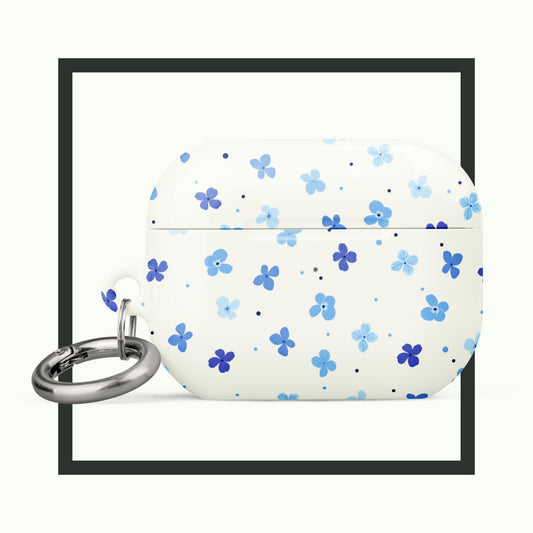 An AirPods® case featuring a soft white background with scattered blue forget-me-not flowers. The case includes a metal carabiner and offers stylish, impact-absorbing protection with a touch of floral elegance. Perfect for practical and beautiful design!